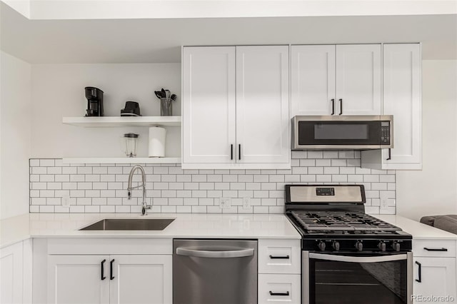 kitchen with open shelves, stainless steel appliances, light countertops, white cabinets, and a sink