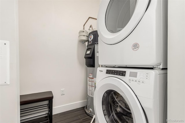 laundry room featuring dark wood-style floors, laundry area, baseboards, and stacked washer / dryer