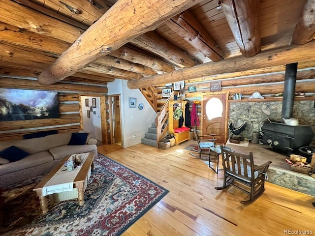 living room with beamed ceiling, a wood stove, log walls, wood ceiling, and light hardwood / wood-style flooring