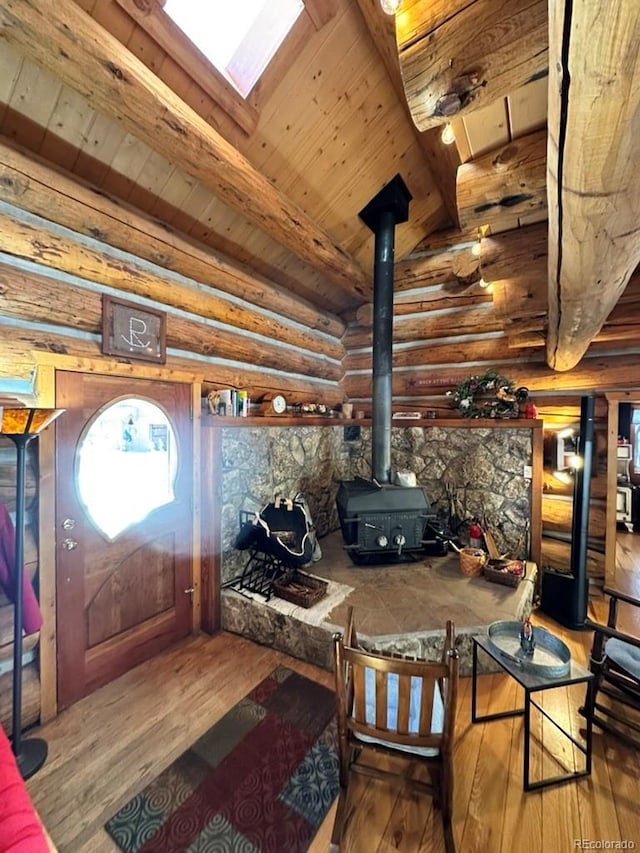 entryway with rustic walls, hardwood / wood-style floors, lofted ceiling with skylight, wooden ceiling, and a wood stove