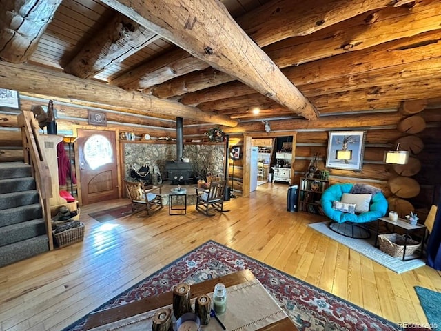 living room featuring beam ceiling, log walls, wood-type flooring, and a wood stove