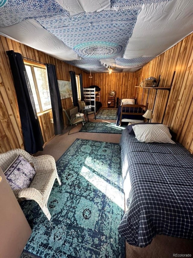 bedroom with wooden walls, a textured ceiling, and carpet flooring