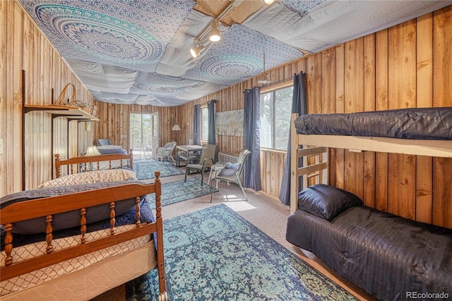 bedroom with carpet floors, access to exterior, and wood walls