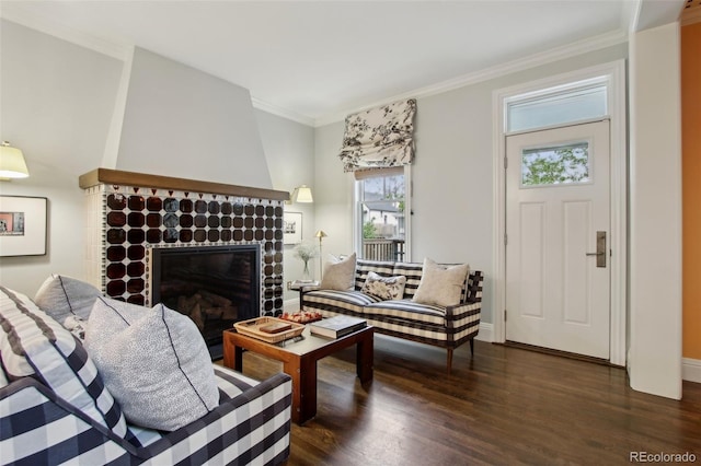 living room with dark wood-type flooring, baseboards, ornamental molding, and a glass covered fireplace