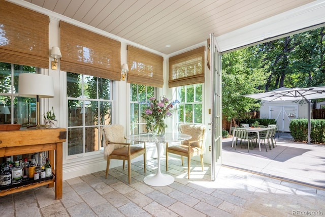 sunroom with ornamental molding, wood ceiling, and stone tile flooring