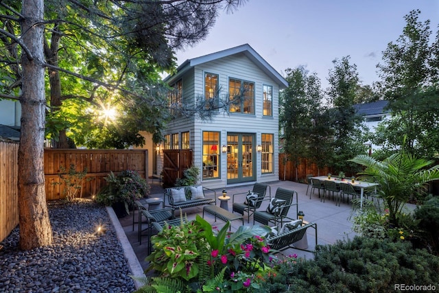 rear view of property featuring outdoor lounge area, fence, french doors, and a patio