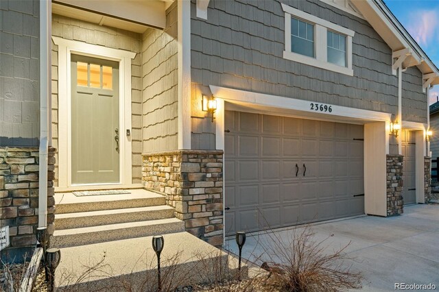23696 E Del Norte Pl, Aurora, CO 80016 - entrance to property featuring stone siding, a garage, and concrete driveway