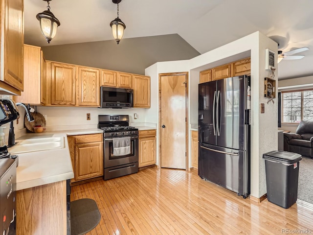 kitchen with a sink, freestanding refrigerator, light countertops, a ceiling fan, and stainless steel gas range