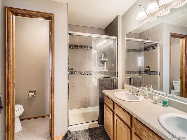 full bath with toilet, double vanity, a sink, and a shower stall