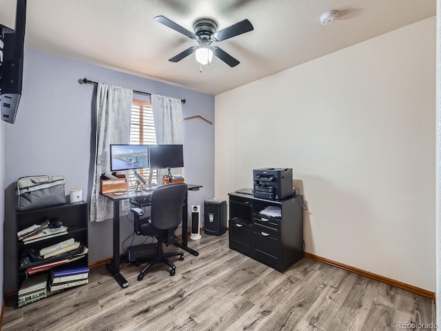 office area with a ceiling fan, baseboards, and light wood-type flooring
