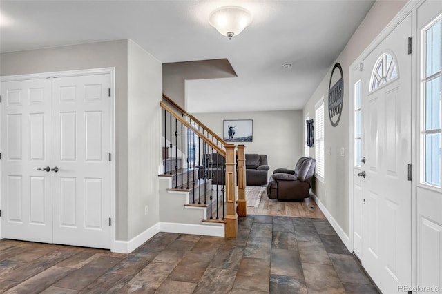 entryway with stone finish flooring, baseboards, and stairway