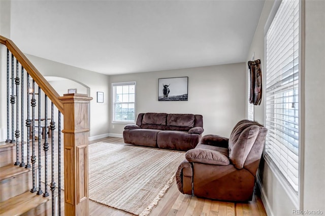 living room featuring wood finished floors, baseboards, and stairway