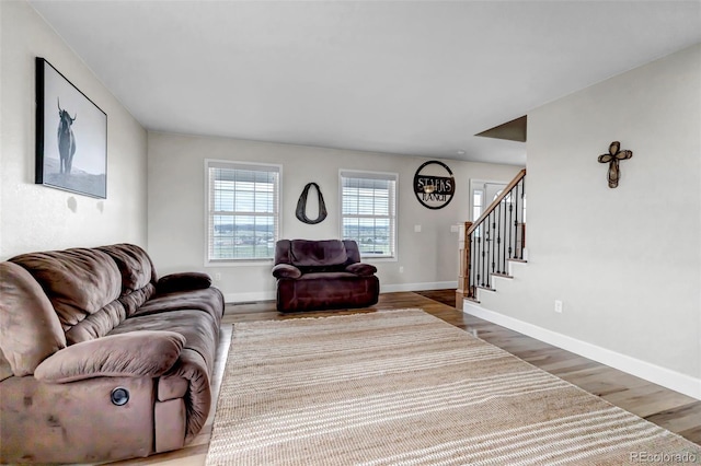 living area featuring wood finished floors, stairway, and baseboards