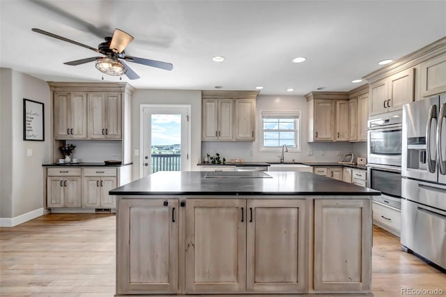 kitchen featuring stainless steel appliances, dark countertops, a center island, a sink, and recessed lighting