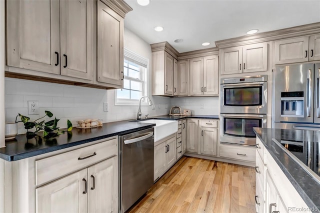 kitchen with appliances with stainless steel finishes, dark countertops, light wood-style floors, recessed lighting, and tasteful backsplash
