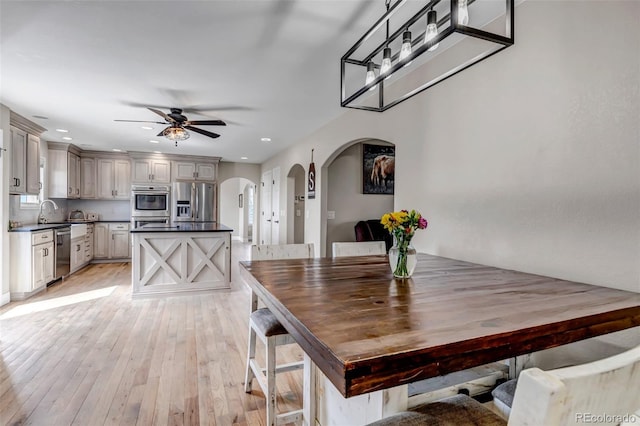 dining room featuring arched walkways, ceiling fan, light wood-style floors, and recessed lighting