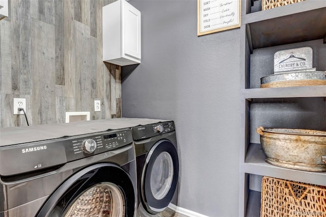 washroom with cabinet space, washer and dryer, and baseboards