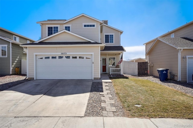 traditional home featuring concrete driveway, an attached garage, fence, and a front yard