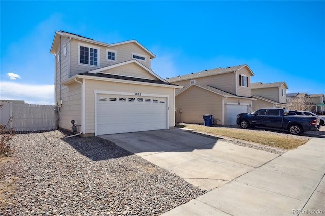 traditional-style home featuring a garage, fence, and concrete driveway