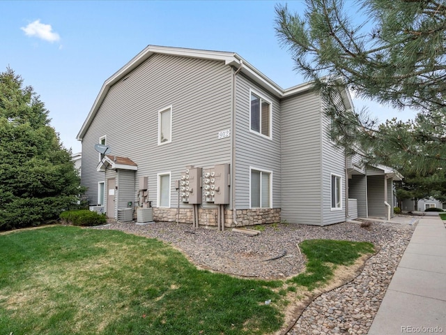 view of home's exterior featuring a lawn, cooling unit, and stone siding