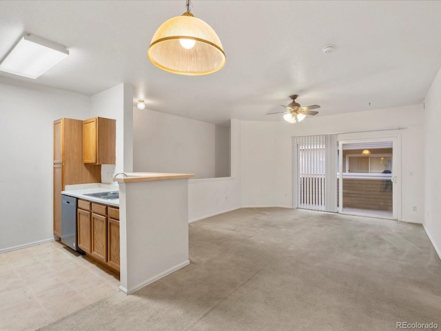 kitchen with ceiling fan, brown cabinetry, stainless steel dishwasher, light countertops, and a sink