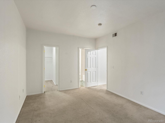 spare room featuring baseboards, light carpet, and visible vents