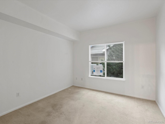 empty room featuring baseboards and light colored carpet