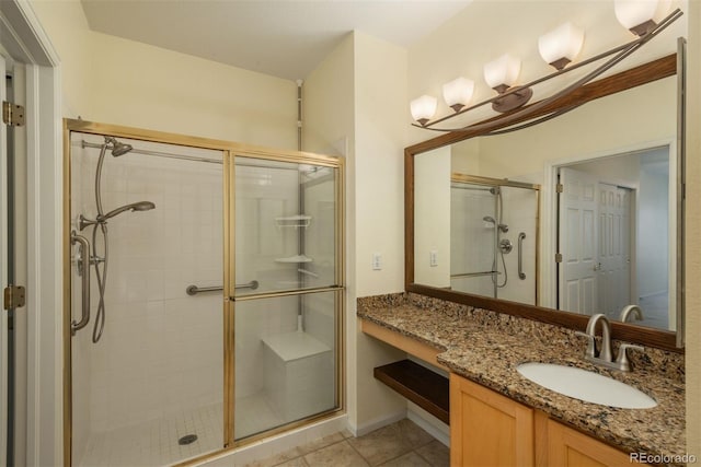 bathroom with an enclosed shower, vanity, and tile patterned flooring