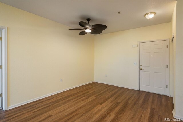 spare room featuring baseboards, dark wood-style flooring, and ceiling fan