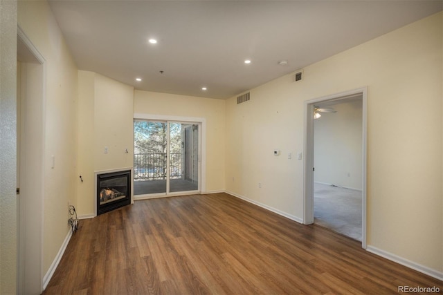 unfurnished living room with a glass covered fireplace, recessed lighting, wood finished floors, and visible vents