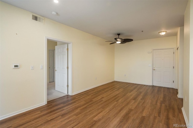 empty room with a ceiling fan, wood finished floors, visible vents, and baseboards