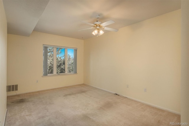 empty room with carpet flooring, a ceiling fan, visible vents, and baseboards