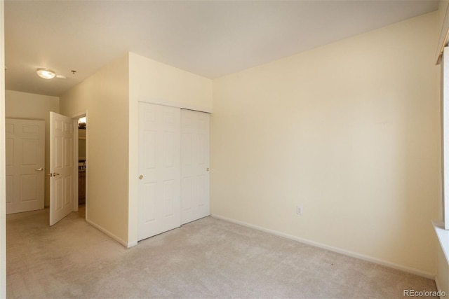 unfurnished bedroom featuring baseboards, light carpet, and a closet