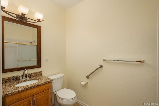 bathroom featuring vanity, toilet, and a shower with door