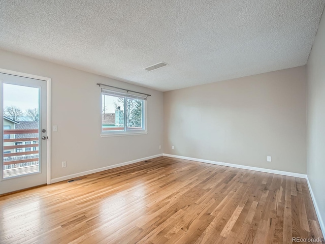 empty room with light hardwood / wood-style flooring and a textured ceiling