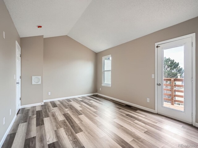 interior space featuring lofted ceiling, light hardwood / wood-style flooring, and a textured ceiling