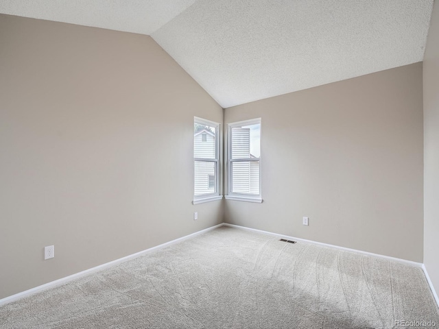 carpeted empty room with vaulted ceiling and a textured ceiling