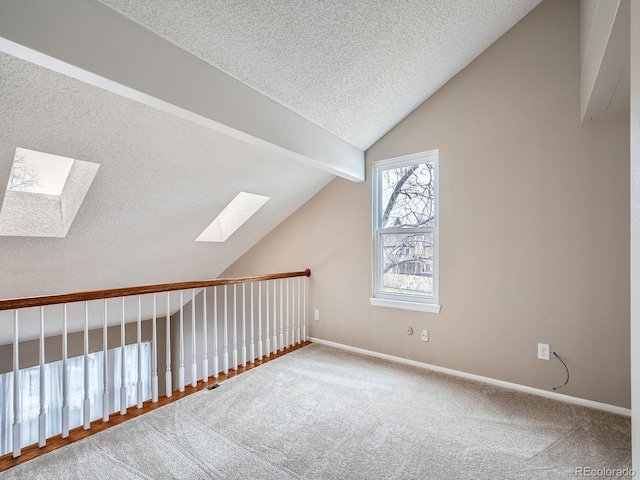 bonus room featuring carpet floors, vaulted ceiling with skylight, and a textured ceiling