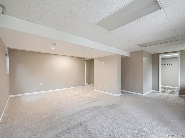 basement featuring light carpet and a drop ceiling