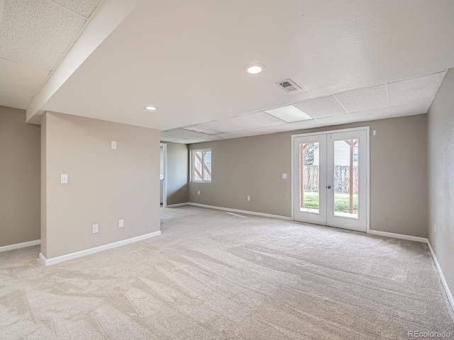 interior space with light carpet, a paneled ceiling, and french doors