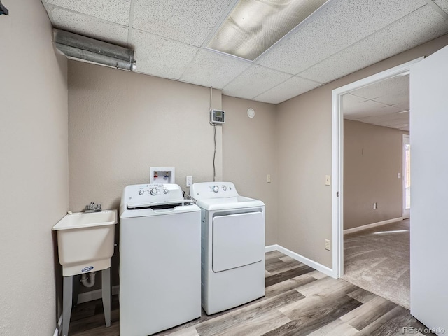 clothes washing area featuring sink, washer and clothes dryer, and light hardwood / wood-style floors