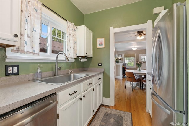 1215 Jackson St, Denver, CO 80206 - kitchen featuring appliances with stainless steel finishes, white cabinets, light countertops, and healthy amount of natural light
