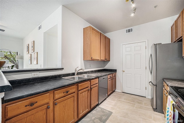 4451 S Ammons St Unit 4-108, Littleton, CO 80123 - kitchen with stainless steel appliances, a sink, brown cabinets, dark countertops, and a textured ceiling