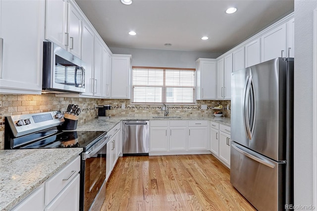 14214 Lakeview Ln, Broomfield, CO 80023 - kitchen featuring appliances with stainless steel finishes, light wood-style flooring, white cabinets, backsplash, and recessed lighting