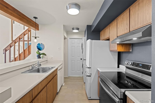 kitchen featuring under cabinet range hood, white appliances, a sink, light countertops, and pendant lighting