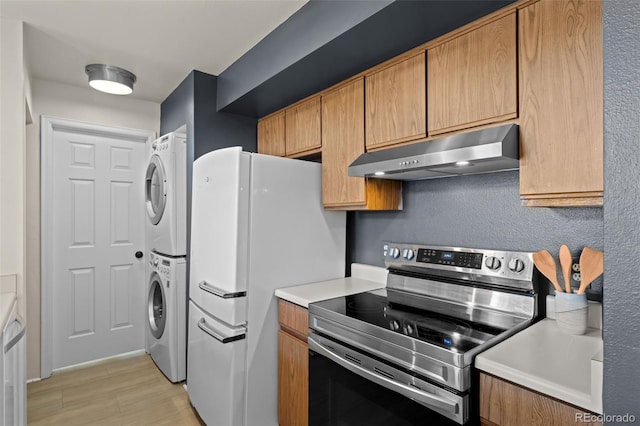 kitchen with stacked washer and clothes dryer, freestanding refrigerator, under cabinet range hood, light countertops, and stainless steel range with electric stovetop