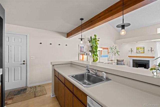 kitchen with decorative light fixtures, a fireplace, light countertops, a sink, and beamed ceiling