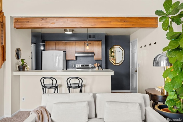 kitchen with electric stove, under cabinet range hood, fridge, pendant lighting, and backsplash