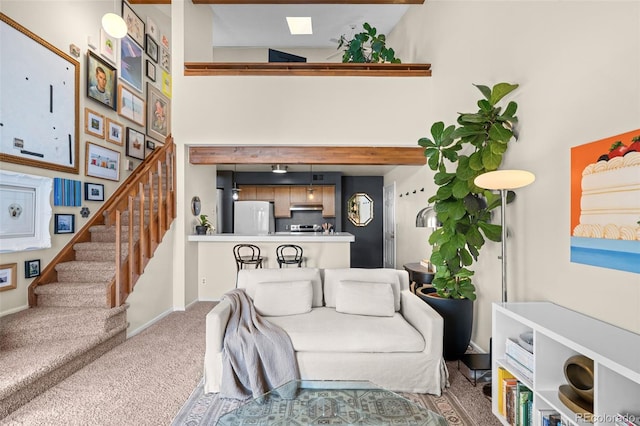 living area with stairs, carpet, a towering ceiling, and baseboards