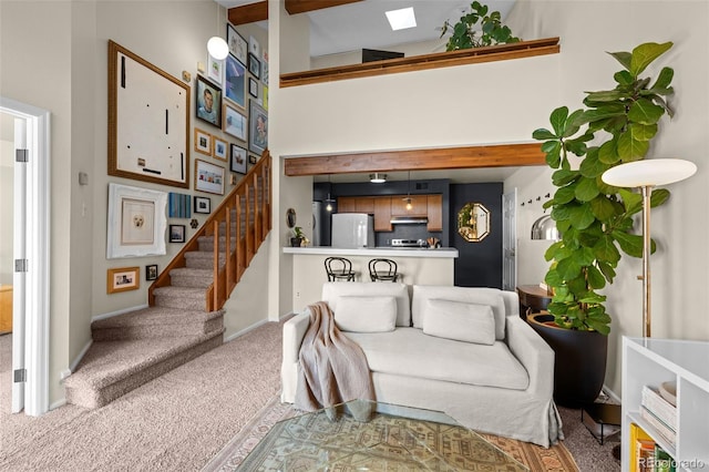 living room featuring stairs, carpet floors, a towering ceiling, and baseboards